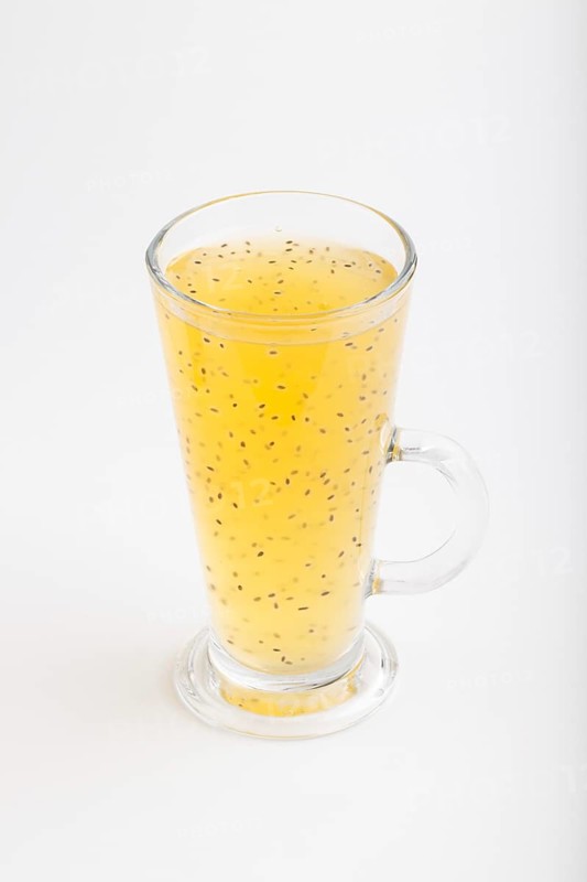 Glass of tangerine orange colored drink with basil seeds isolated on white background. Morninig, spring, healthy drink concept. Side view