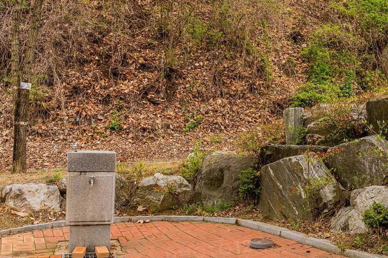 Water fountain in public park next to stack of large boulders in South Korea