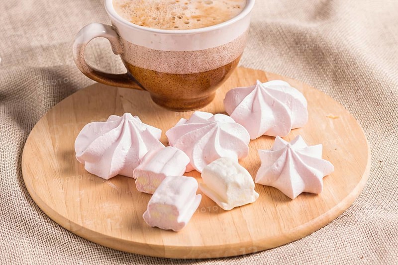 Sweet buns, meringues and coffee cup on a wooden board and linen tablecloth