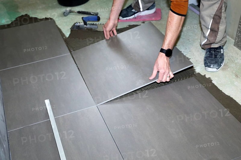 Tiler lays modern large floor tiles in a bathroom