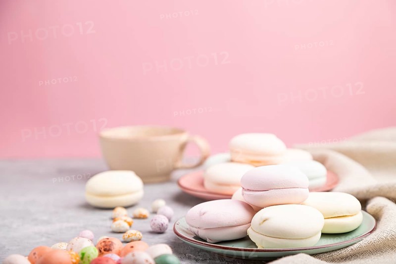 Colored zephyr or marshmallow with cup of coffee and dragees on a gray and pink background and linen textile. Side view, close up, selective focus, copy space