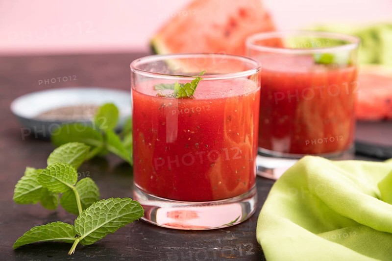 Watermelon juice with chia seeds and mint in glass on a black concrete background with green textile. Healthy drink concept. Side view, close up, selective focus