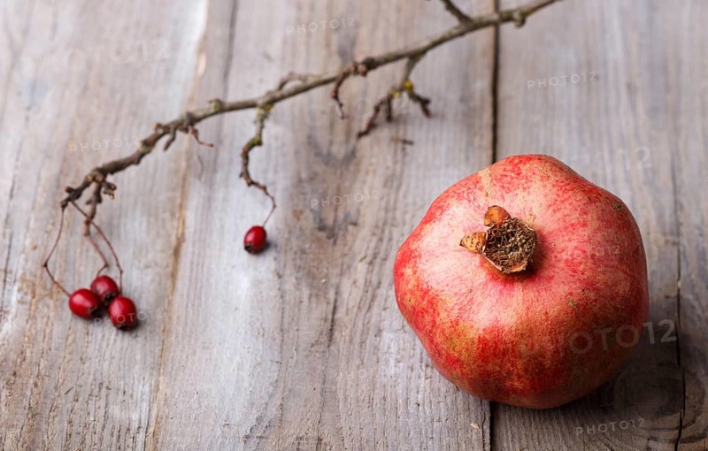 Ripe garnet with a branch on a rustic wooden background