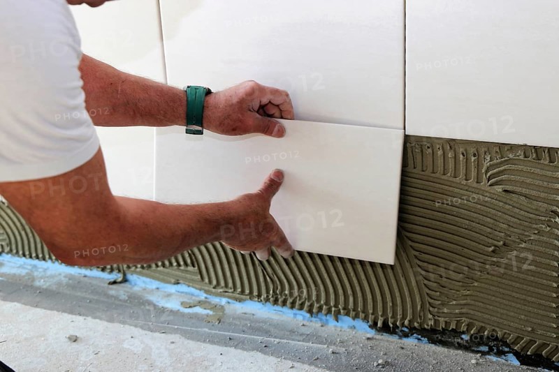 Tiler lays modern wall tiles