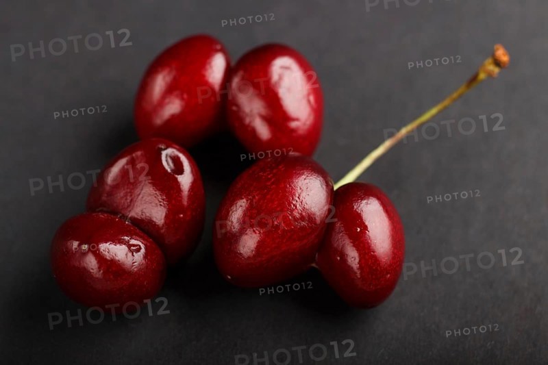 Ugly weird red sweet cherry on black background. side view, close up, macro, trendy