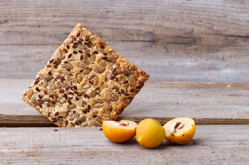 Biscuits with flax, sesame and sunflower seeds and yellow quince fruit on a rustic wooden background