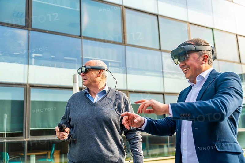 Senior and mature businessmen using the VR headset with actions outdoors next to a financial building
