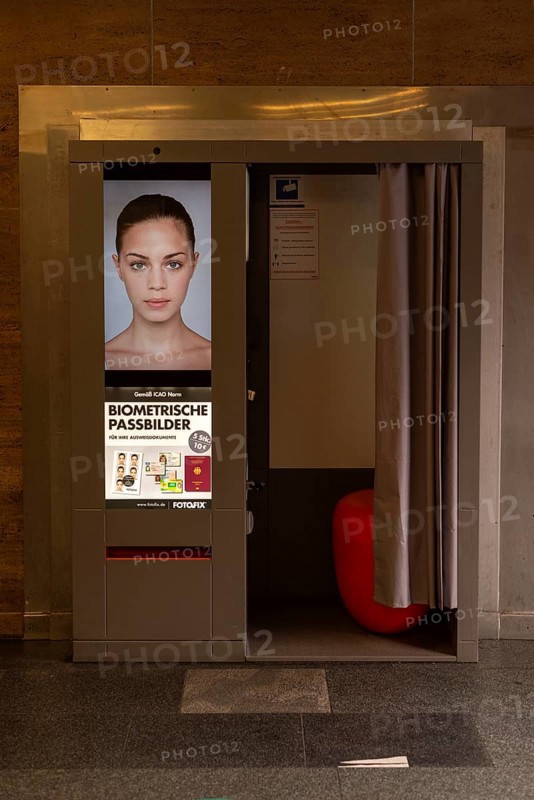 A photo booth for biometric passport photos with a female face on the advertising poster, Magdeburg, Saxony-Anhalt, Germany, Europe