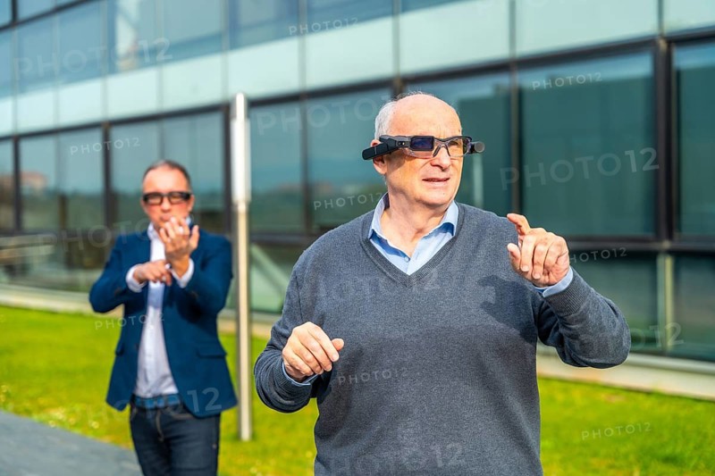 Businessman experiencing with augmented mixed vision headset in an urban park next to financial building