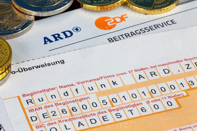 Symbolic image of the licence fee, contribution service: Close-up of a letterhead with ARD logo and ZDF logo and a remittance slip and coins