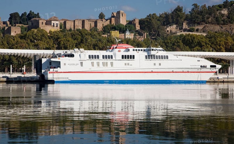 Alcantara Dos catamaran ferry at the quayside in new port development in Malaga, Spain with the historic Alcazaba fortress behind