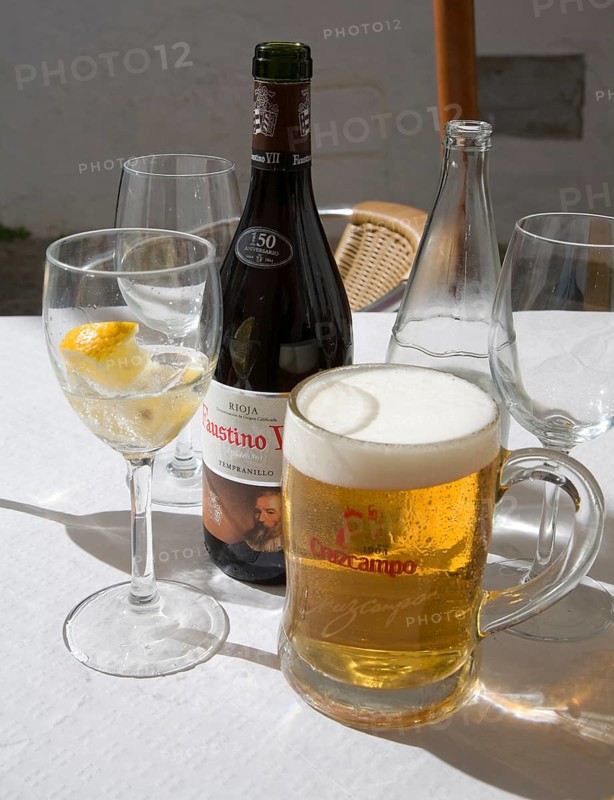 Beer and iced water glasses and wine bottle on restaurant table in Spain