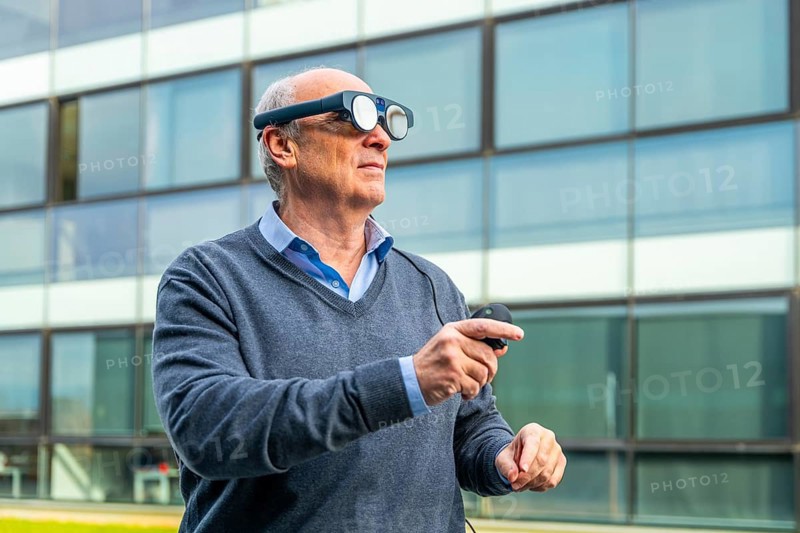 Aged man using futuristic augmented mixed vision headset outdoors