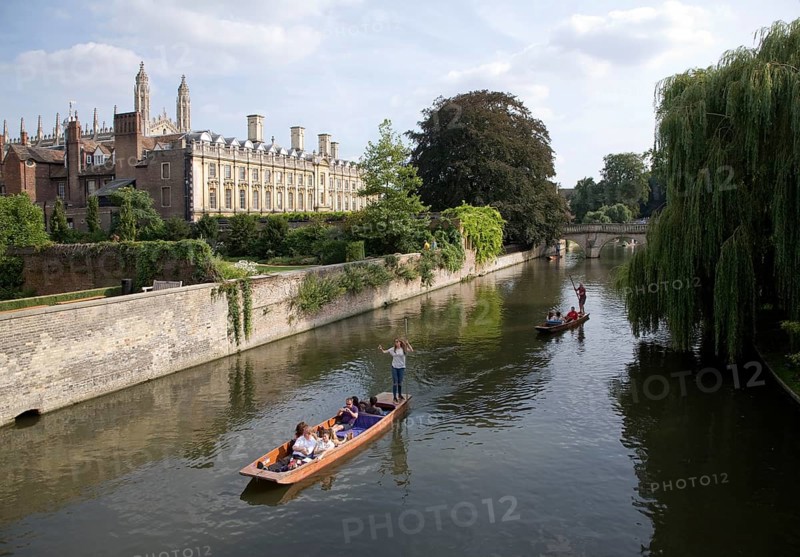 People punting in small boats on the River Cam, Cambridge England with Clare College in the background
