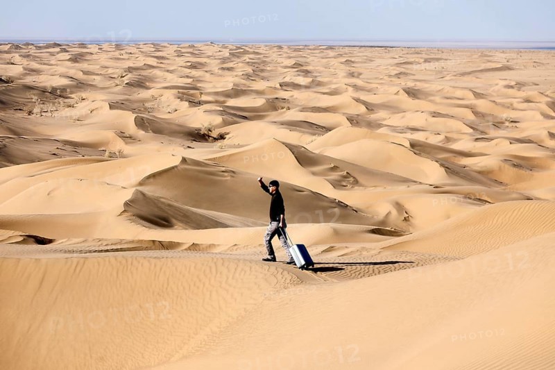 Symbolic image, tourist with suitcase in the desert, Mesr Desert, Iran. The Mesr Desert is part of the central Dashte-Kavir desert, 12.03.2019