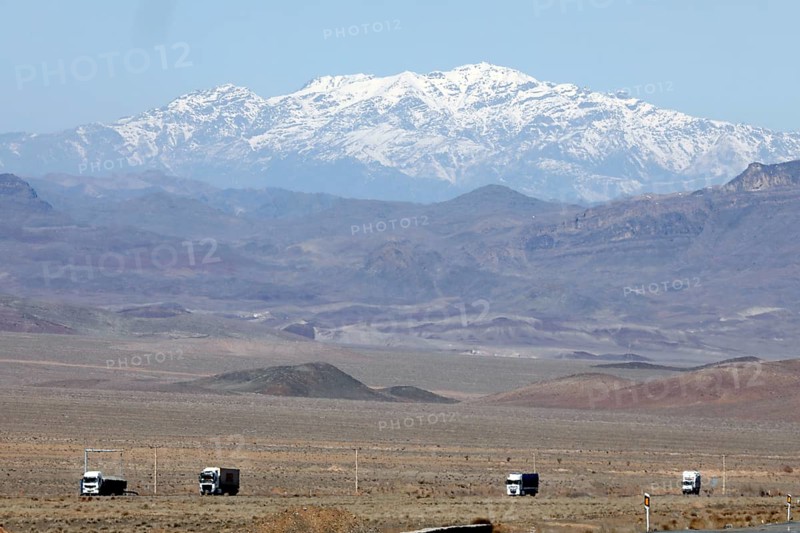 Truck on a motorway in the central desert of Iran, snow-capped mountains can be seen in the background, 13.03.2019