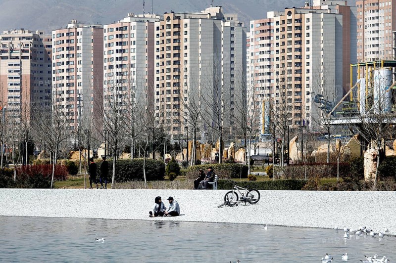 A young couple sits on the beach of Lake Chitgar in Tehran, Iran. Lake Chitgar is a man-made lake in the north-west of Tehran, also known as the Lake of the Martyrs of the Persian Gulf, 10 March 2019