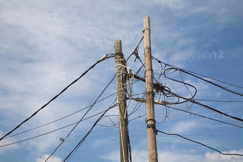 Confused tangle electricity phone line cables telegraph pole blue sky