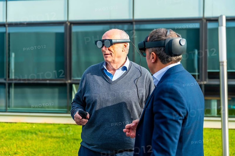 Two aged businessmen partners testing virtual reality headset outdoors in a sunny day