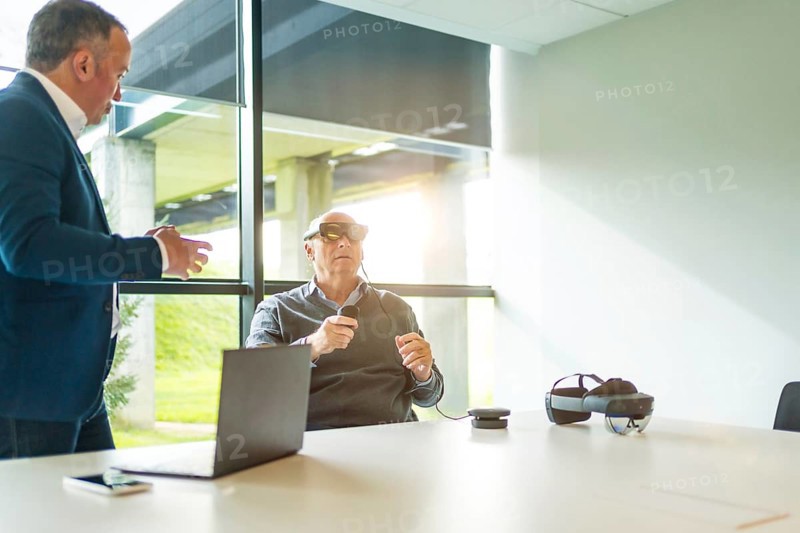 Businessman talking with client during a demo of new vr goggles in the office