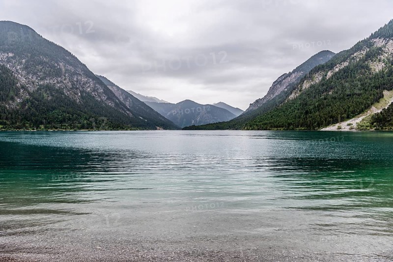 A peaceful lake surrounded by mountains under a cloudy sky, Plansee, Heiterwang, Tyrol, Austria, Europe