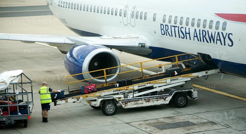 Baggage handler loading luggage onto British Airways plane at gatwick airport, London, England, United Kingdom, Europe