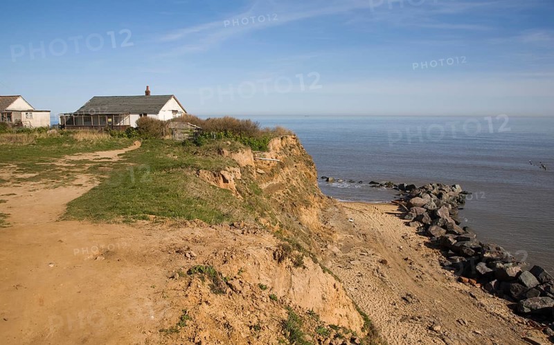 Cliff top buildings at risk of coastal erosion, Happisburgh, Norfolk, England with beach rock armour defences