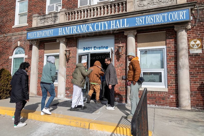 Hamtramck, Michigan USA, 25 February 2024, Abraham Aiyash (holding door), Majority Floor Leader in the Michigan House of Representatives, took residents who had not yet voted into City Hall where early voting was in progress. They had come from a rally in this heavily Arab-American city which urged a vote for uncommitted instead of for Joe Biden. Many Arab-Americans are furious about Biden's support for Israel in the Gaza war. Israel's bombing there has cost tens of thousands of Palestinian lives