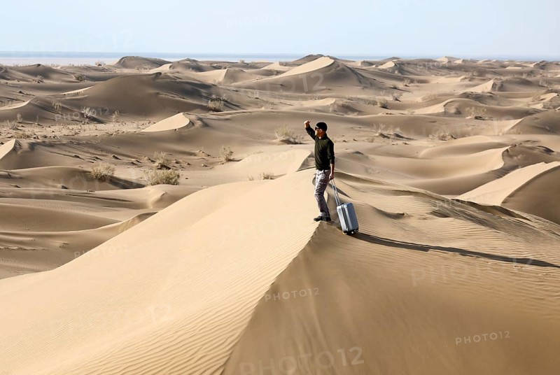 Symbolic image, tourist with suitcase in the desert, Mesr Desert, Iran. The Mesr Desert is part of the central Dashte-Kavir desert, 12.03.2019