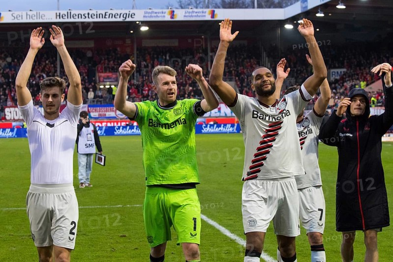 Football match, the Bayer Leverkusen players from left to right: Josip STANISIC, goalkeeper and captain Lukas HRADECKY, Jonathan TAH, Jonas HOFMAN hidden and Florian WIRTZ celebrate the victory with their travelling fans in the fan curve, Voith-Arena football stadium, Heidenheim