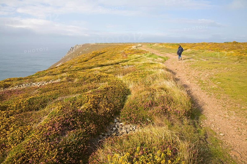 Woman wearing kagoule walking along the South West coast path at St Agnes head, Cornwall, England, United Kingdom, Europe