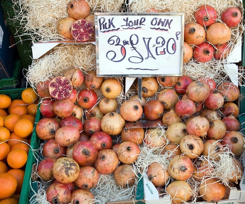 Pomegranates for sale on market stall three for one pound twenty pence