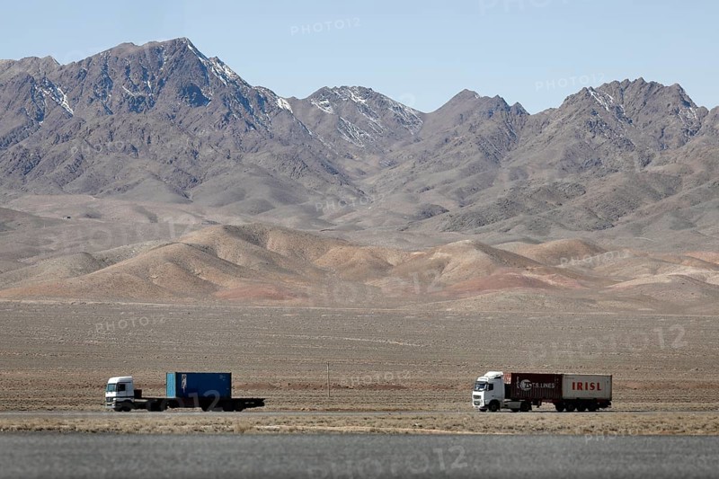 Truck on a motorway in the central desert of Iran, snow-capped mountains can be seen in the background, 13.03.2019