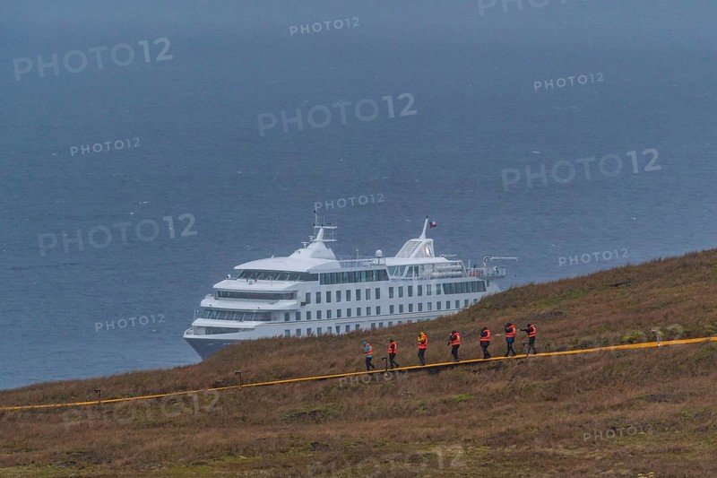 Passengers of the cruise ship Stella Australis in life jackets hike in storm and rain to Cape Horn, southernmost point of America, Horn Island, Cabo de Hornos National Park, Tierra del Fuego, Patagonia, Chile, South America
