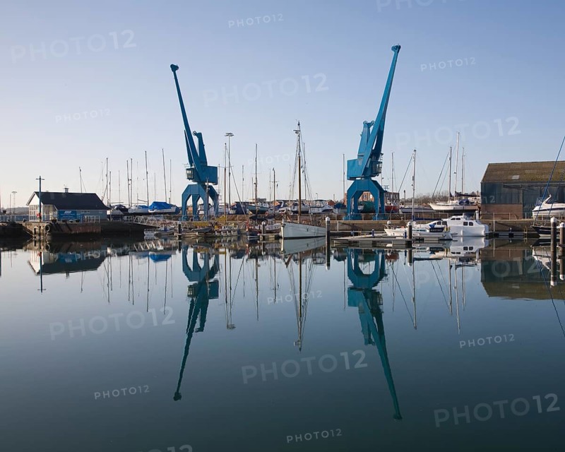 Two large blue industrial cranes reflected in water of Wet Dock marina, Ipswich, Suffolk, England, United Kingdom, Europe