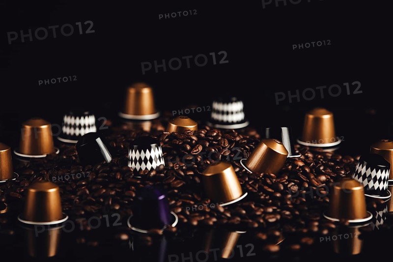 Scattered coffee capsules and coffee beans on a dark background