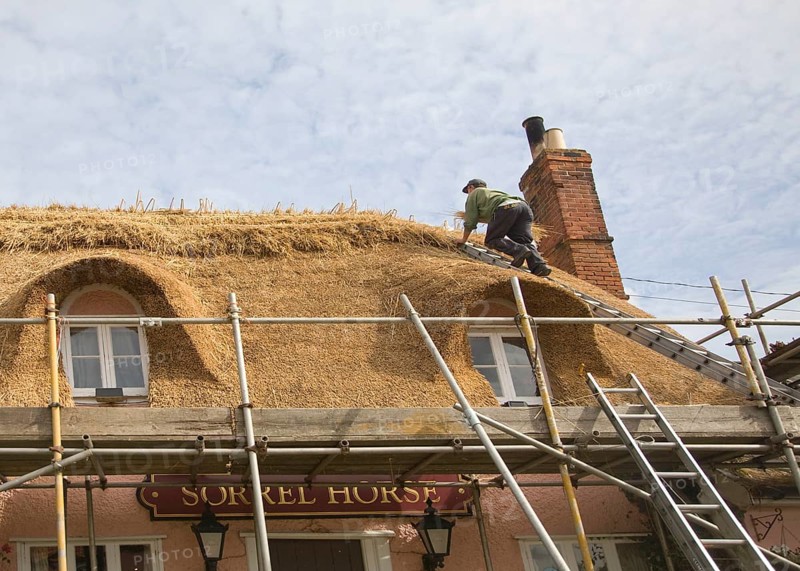 A thatcher completing the re-thatching of a traditional country pub, the Sorrel Horse, Shottisham, Suffolk, England, United Kingdom, Europe