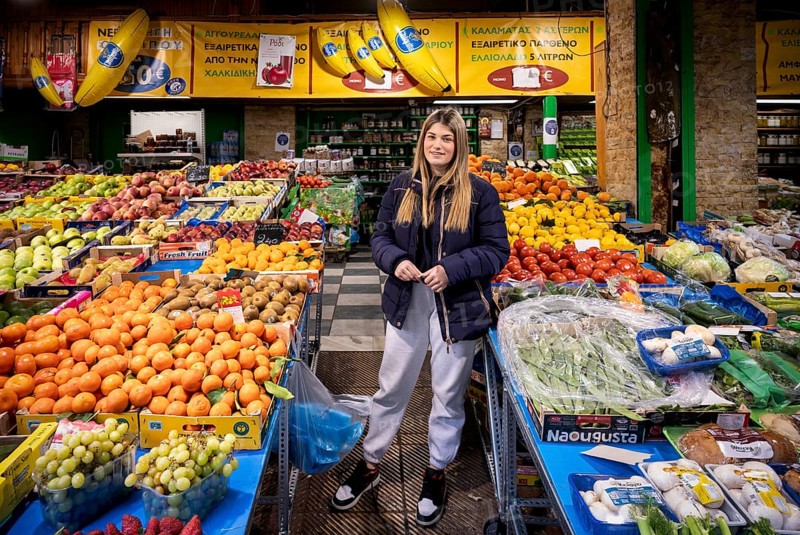 Trader, fruit seller, young woman, posing proudly in front of her market stall, display of fresh fruit, oranges, pineapples, bananas, kiwi, apples, plums, fruit seller, food, Kapani market, Vlali, Thessaloniki, Macedonia, Greece, Europe