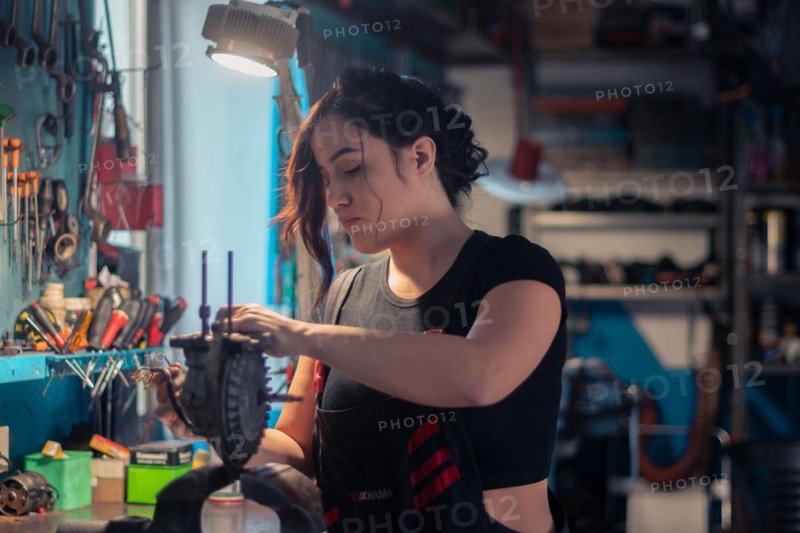 A craftswoman is carefully engaged in repair work, surrounded by tools in her occupation, a complete tool panel in background with bokeh effect, traditional male jobs by Mixed-race latino woman