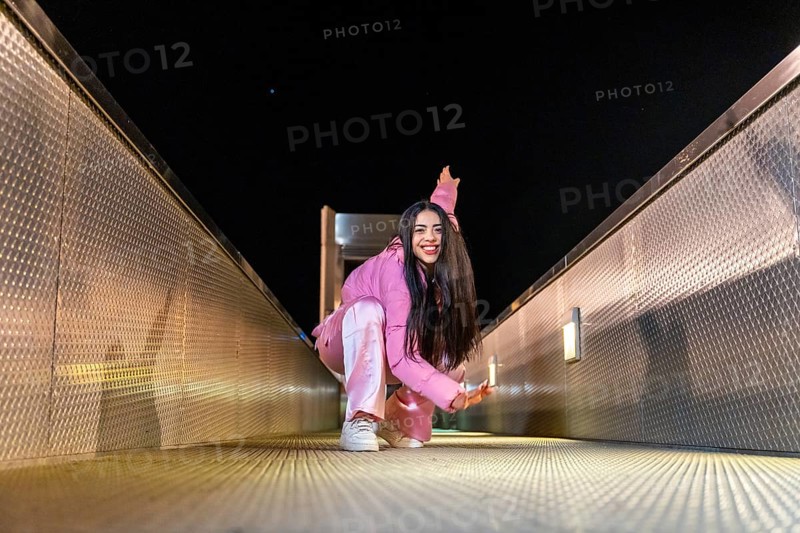 Low angle view portrait of an active free style dancer performing sitting on a bridge at night