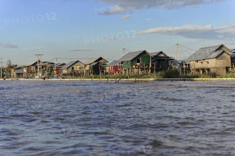 Stilt houses on the edge of a river with golden evening light, Inle Lake, Myanmar, Asia