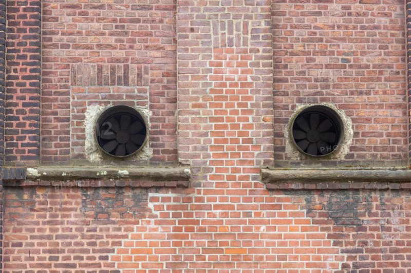 Old brick facade with round ventilation openings in the wall