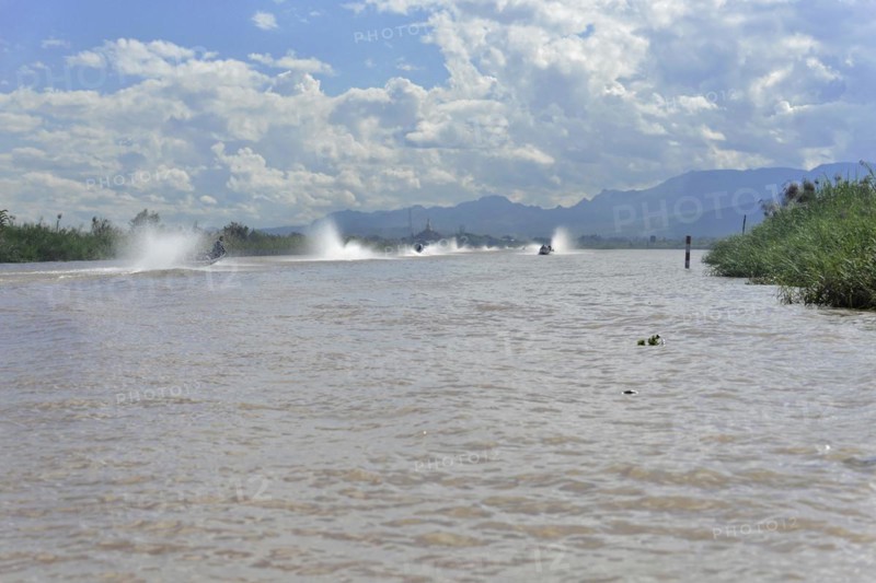 Speedboats create water fountains on a river with cloudy sky in the background, Inle Lake, Myanmar, Asia