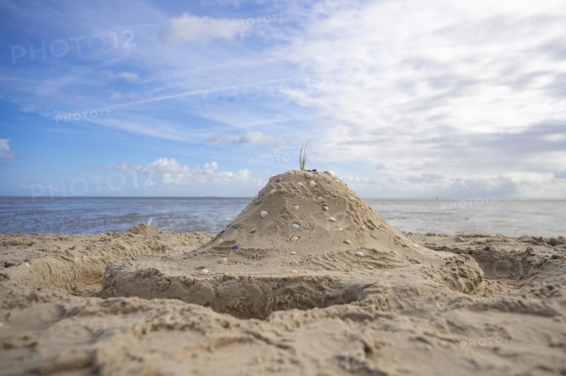 Sandcastle with shells and moat on the beach, in the background sea and blue sky, Schillig, Wangerland, North Sea, Germany, Europe