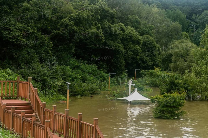 White awning over flooded river where picnic table has been submerged under water from monsoon rains in Daejeon South Korea