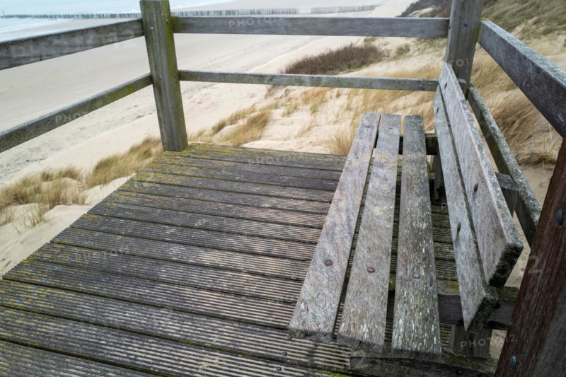 Old wooden bench on a footbridge with a view of the dune landscape