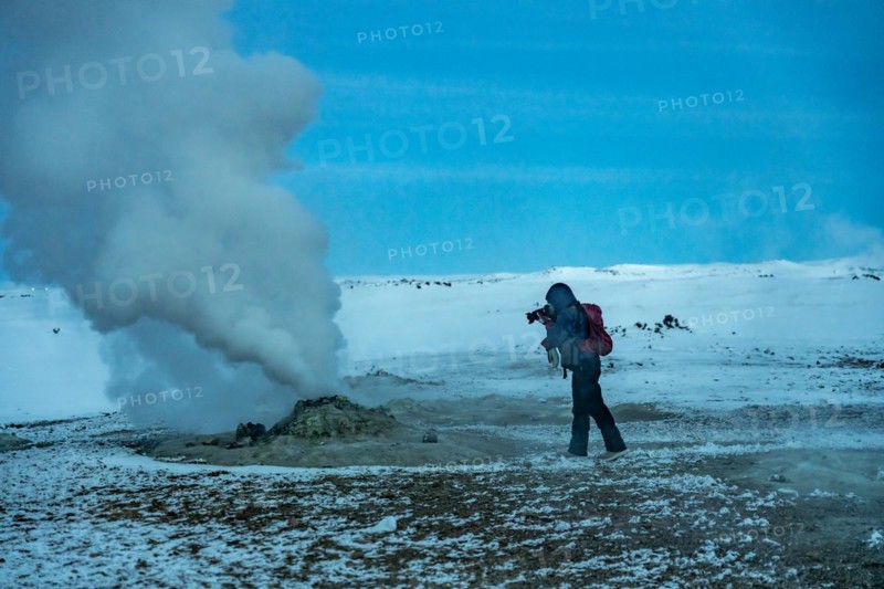 Adventurous photographer woman in winter in Iceland photographing in the Hverir or Namafjall Geothermal Area