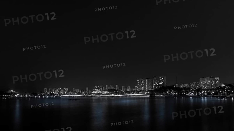 A serene black and white night shot of city skyline reflections on water, in South Korea