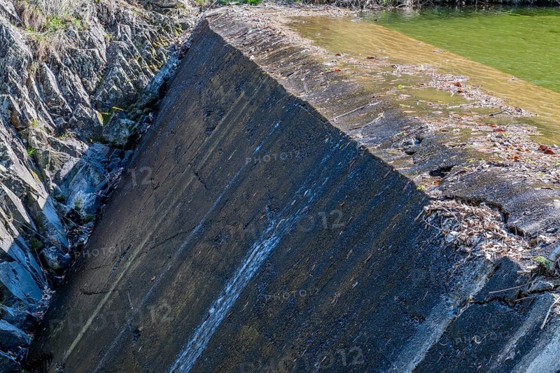 Water trickles down a concrete dam scattered with leaves, in South Korea