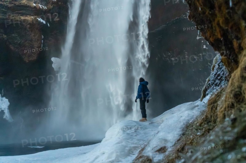 Silhouette of woman in winter in Iceland visiting Skogafoss waterfall